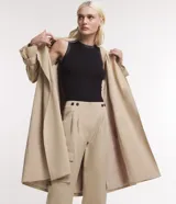 Trench coat largo color beige, de gabardina, con cuello con solapas, doble botonadura, lazo en la cintura, mangas largas con cintas en los puños y bolsillos delanteros.