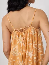 Vestido corto negro con estampado de palmeras, soles y estrellas en color crema. Diseño suelto con breteles finos y escote recto con lazo ajustable.