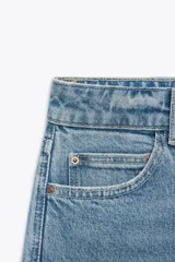Jeans de tiro alto color celeste, corte mom fit, con cinco bolsillos y cierre frontal con cremallera y botón.