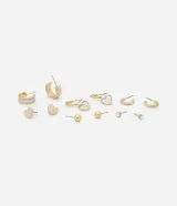 Set de aros dorados con diferentes diseños: aros tipo argolla con borde plateado, aros tipo argolla con dije de corazón plateado, aros pequeños con textura, aros tipo botón con forma de corazón plateado, aros tipo botón con esfera dorada y aros tipo botón con strass.