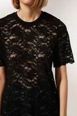 Top negro de encaje con mangas cortas, cuello redondo y corte holgado.