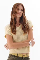 Chaleco de punto en color beige, con diseño de ochos y corte holgado.