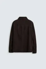 Sobrecamisa marrón de cuero gamuzado, corte recto, con cuello clásico, cierre frontal con botones, mangas largas con puños abotonados y bolsillos de parche en el pecho.