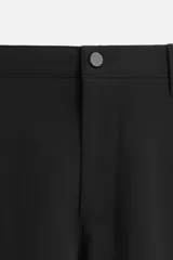Pantalón negro de corte slim fit, confeccionado en tejido elástico. Cuenta con cintura elástica, bolsillos frontales y traseros de vivo. Cierre frontal con cremallera y botón.