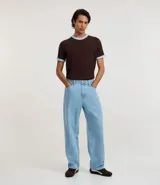 Remera de algodón de corte regular, color blanco hueso, con cuello redondo y ribete negro. Presenta un diseño de doble raya negra en las mangas y ribetes negros en el cuello y los puños de las mangas.