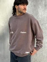 Buzo marrón con estampado en la espalda que incluye un sol, la palabra "Osten" y las frases "Empower Elevate Your" y "Boldness Strenght".