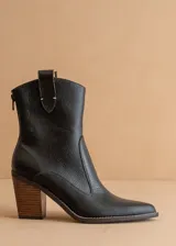 Bota corta de cuero negro con puntera fina, caña media y cierre lateral. Tiene un tirador trasero y un tacón de madera.