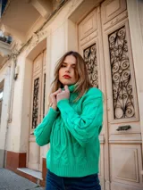 Polera blanca de punto con cuello alto y diseño trenzado.