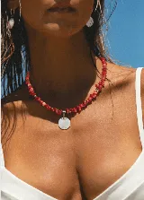 Collar corto de cuentas de coral rojo irregular, con detalles de pequeñas cuentas plateadas y dije circular de nácar.