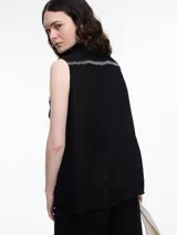 Camisa sin mangas negra de lino con cuello clásico, cierre frontal abotonado y bolsillo de parche en el pecho. Presenta bordados tipo pespunte en contraste en el frente y canesú trasero.