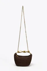 Bolso mini trenzado color marrón con asa de mano dorada metálica y doble asa bandolera ajustable y extraíble. Tiene forro, bolsillo interior y cierre mediante cremallera.