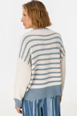 Sweater de punto color crudo con cuello redondo y terminaciones en celeste.