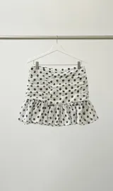 Minifalda blanca con lunares negros, de crepé con cierre trasero y volados en el ruedo.