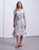 Vestido midi estampado con flores color celeste y beige, escote cruzado, mangas cortas con puños elastizados, cintura elastizada con lazo de ajuste.