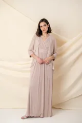 Vestido largo de lurex rosa pálido, corte cruzado con faja en la cintura. Incluye casaca de gasa suelta con puños de lurex a juego.