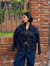 Campera de jean azul oscuro con costuras en hilo ocre, corte recto, cuello clásico, bolsillos frontales con solapa y cierre con botones metálicos.