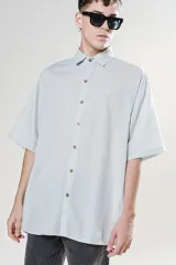 Camisa de manga corta color verde agua, con cuello clásico y calce oversize. Presenta un canesú en la espalda.