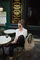 Bolso tipo hobo de cuero color beige, con asa anudada al hombro y cierre superior con cremallera.