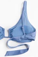 Top de bikini celeste con breteles ajustables, alambre de metal en forma de U en el busto y tiras para atar en la espalda. Copas con rellenos extraíbles que moldean el busto y proporcionan una buena sujeción. Sin aros. Forrado.