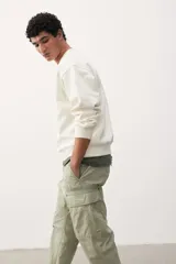 Pantalón cargo color verde claro, de corte relajado, con bolsillos laterales con solapa y botón a presión. Confeccionado en popelina de algodón con elástico en la parte posterior de la pretina y cierre con botón a presión.