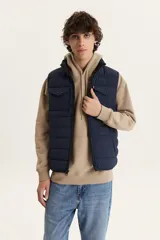 Chaleco puffer azul marino con cierre frontal, cuello alto y dos bolsillos con solapa en el pecho.