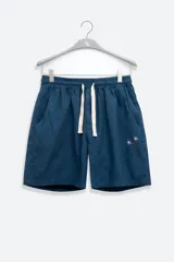 Short azul de lino y algodón con cintura elástica ajustable con cordón. Tiene bolsillos laterales y un bolsillo trasero tipo parche. Presenta un bordado floral en la pierna izquierda.