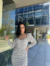 Vestido midi blanco con lunares negros, escote cuadrado, mangas largas abullonadas y corte ajustado.