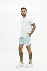 Short de baño celeste con estampado de hojas blancas. Tiene cintura elástica con cordón ajustable, dos bolsillos laterales y uno trasero.