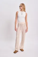 Pantalón de punto crochet color crudo, de corte recto y cintura alta con cordón ajustable.