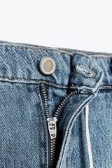 Pantalón de jean de tiro medio, pierna ancha y largo hasta el tobillo. Cintura con trabillas ajustable con cordones a contraste. Cinco bolsillos. Efecto lavado. Cierre frontal con cremallera y botón.