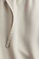 Pantalón color beige de lyocell, corte recto, con cintura elastizada y cordón ajustable.