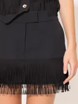 Minifalda negra con flecos en el ruedo, bolsillos laterales y traseros.