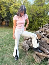 Pantalón blanco de mezclilla, corte acampanado con abertura frontal en el bajo de la pierna. Se lleva con un cinturón blanco de hebilla redonda.