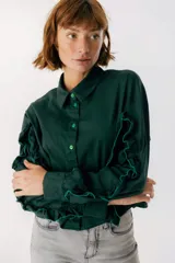 Camisa celeste con cuello clásico, cierre frontal con botones y mangas largas con volados.