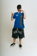 Bermuda de felpa negra con efecto lavado (washed) que aclara hacia los laterales. Presenta un gran estampado serigrafiado en blanco con motivos florales y caracteres orientales estilizados. Posee cordón de ajuste en la cintura y remaches metálicos cromados en los laterales.