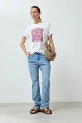 Remera blanca de algodón con estampado de flores rosadas y texto 'LET LOVE IN'.