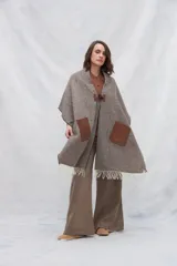 Chal de lana fina sin teñir, con calce en hombros, abrochadura con alamar de fieltro, bolsillos de cuero y terminación con flecos. Diseño exclusivo de Don Baez, hecho en Uruguay.