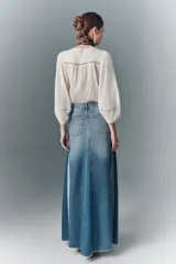 Falda larga acampanada de denim rígido con diseño patchwork en distintos tonos de azul y ruedo desflecado.