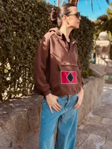 Canguro color chocolate de algodón con cierre parcial en el cuello y bolsillo frontal con apliques geométricos bordados a mano en terciopelo rojo y verde.