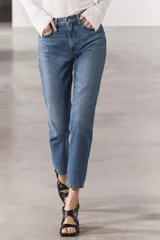 Jeans de tiro medio con corte recto, color azul denim con efecto lavado. Cuenta con cinco bolsillos, trabillas en la cintura y cierre frontal con cremallera y botón metálico.