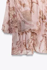 Top corto de bambula color rosa con estampado paisley en tonos dorados. Tiene escote recto, tirantes finos con volantes y cierre en la espalda con botones forrados.