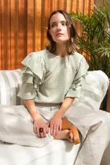 Blusa de spandex con estampado vichy en tonos pistacho y blanco, con mangas al codo adornadas con tres volados y puños elásticos. Cierre con botón en la parte posterior.