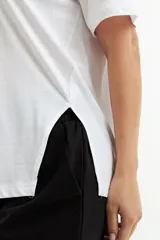 Remera blanca de algodón con cuello redondo y mangas cortas, corte recto y tajo lateral.