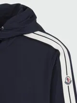 Campera azul marino con capucha y cierre frontal, con dos líneas blancas en las mangas y logo de la marca en el brazo izquierdo.