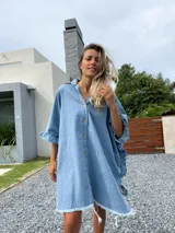 Camisola tipo poncho en jean celeste, con cuello camisero, abotonadura frontal y mangas cortas con volados.
