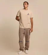 Remera de algodón color beige, de corte recto y manga corta. Estampa en la espalda con el personaje Pato Lucas disfrazado de esqueleto y la frase "Trick or Treat" en letras azules.