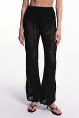 Pantalón negro de tejido crochet calado con diseño patchwork y corte acampanado.