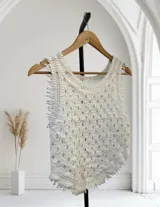 Musculosa blanca de tejido de punto crochet, con diseño calado y flecos en el ruedo y los bordes de las sisas.