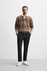 Pantalón negro de corte slim fit, confeccionado en tejido elástico. Cuenta con cintura elástica, bolsillos frontales y traseros de vivo. Cierre frontal con cremallera y botón.