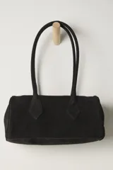 Bolso tubular de gamuza color negro, con asas cortas y detalles de costura en los extremos.